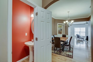 Dining room featuring light wood-style floors, a chandelier, ornamental molding, arched walkways, and a ceiling fan