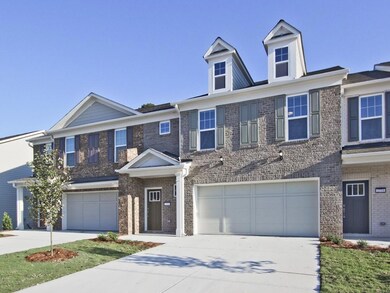 View of property with an attached garage, concrete driveway, and brick siding