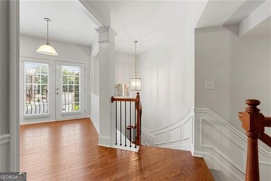 Foyer with wood-type flooring, a decorative wall, wainscoting, and french doors