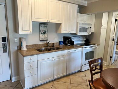 Kitchen featuring white appliances, sink, light ti