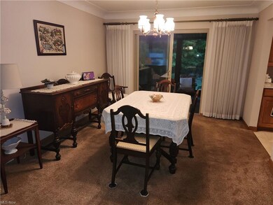 Carpeted dining area featuring a notable chandelier and crown molding