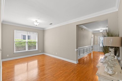 Dining room featuring crown molding, light wood-type flooring, and a wainscoted wall