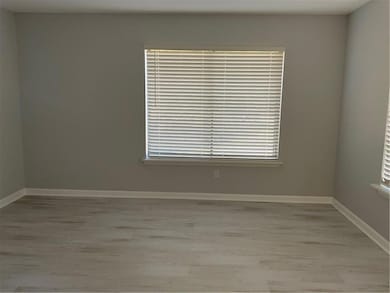Spare room featuring light wood-style flooring and baseboards