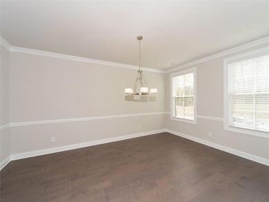 Unfurnished room featuring a chandelier, dark wood-type flooring, ornamental molding, and baseboards