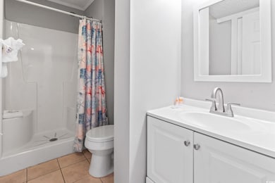 Full bath with light tile patterned floors, a stall shower, and vanity