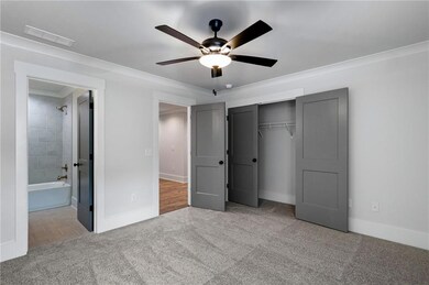 Unfurnished bedroom featuring light colored carpet, a closet, ceiling fan, and crown molding
