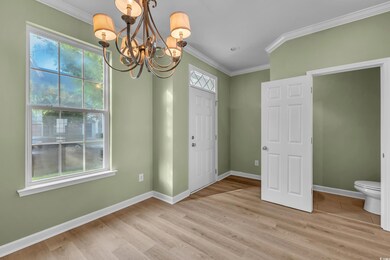 Unfurnished dining area featuring a chandelier, crown molding, and light wood finished floors