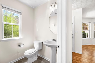 Half bath featuring wood finished floors, healthy amount of natural light, and a textured ceiling