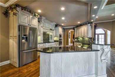 DREAM KITCHEN WITH ALL OF THE NECESSITIES-CUSTOM GLAZED CABINETRY WIH TILED BACKSPLASH ILLUMINATED BY UNDER CABINET LIGHTING, GRANITE COUNTERS & TWO DIFFERENT BAR HEIGHTS FOR ADDTL SEATING, HIDDEN WALK-IN PANTRY & BUILT-IN CONVECTION OVEN & MICROWAVE