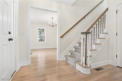 Entryway featuring light wood flooring, a chandelier, and stairs