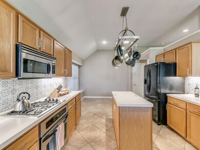 Kitchen featuring tile floors, a kitchen island, stainless steel appliances, and decorative backsplash