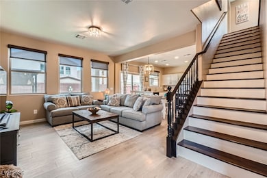 Living area with stairway, a chandelier, light woo