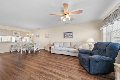 Living room featuring a chandelier, wood finished floors, a ceiling fan, and baseboards