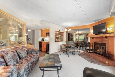 Living room featuring a chandelier, carpet, a fireplace, and a textured ceiling