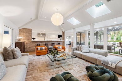 Oversized floor-to-ceiling picture windows, which span almost the entire length of the back of the home, fill the space with natural light. Effortless connection to the kitchen enhances both functionality and entertaining potential.