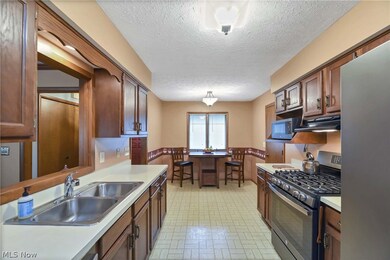 Kitchen featuring pendant lighting, light floors, sink, appliances with stainless steel finishes, and a textured ceiling