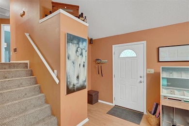 Foyer featuring wood finished floors, stairway, and lofted ceiling