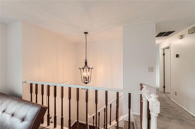 Stairway featuring a textured ceiling, carpet, and baseboards