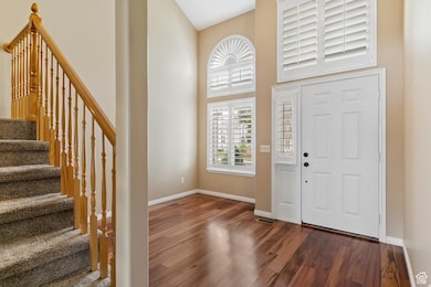 Entryway featuring stairway, dark wood-type flooring, and a towering ceiling