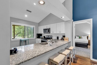 Kitchen with stainless steel appliances, a kitchen breakfast bar, white cabinetry, light stone counters, and recessed lighting