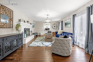 Living area featuring hardwood / wood-style flooring, a chandelier, and a brick fireplace