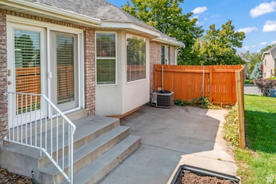 View of private patio with air conditioning unit, bay window and rear entrance with blinds