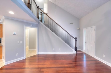 Entrance foyer with high vaulted ceiling, stairs, light wood-style floors, and a textured ceiling