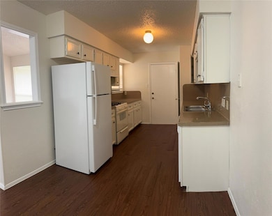 Kitchen with a textured ceiling, white appliances