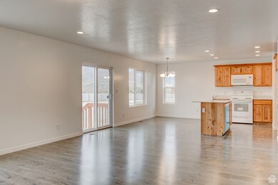 Kitchen featuring a textured ceiling, a chandelier, white appliances, recessed lighting, and open floor plan
