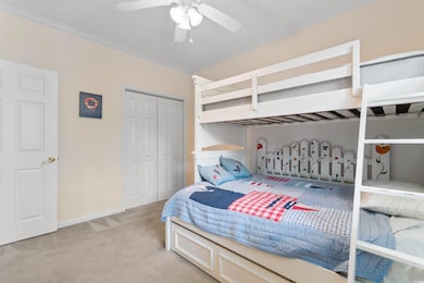 Bedroom with crown molding, light colored carpet, baseboards, a closet, and ceiling fan