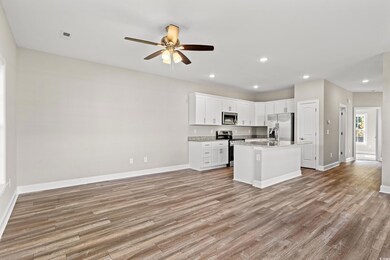 Kitchen featuring white cabinets, ceiling fan, an island with sink, stainless steel appliances, and light hardwood / wood-style floors