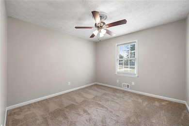 Carpeted spare room with a textured ceiling and ceiling fan