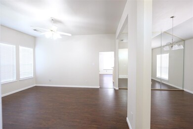 Spare room featuring dark hardwood / wood-style floors and ceiling fan with notable chandelier