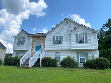 Split foyer home with a front lawn and stone siding