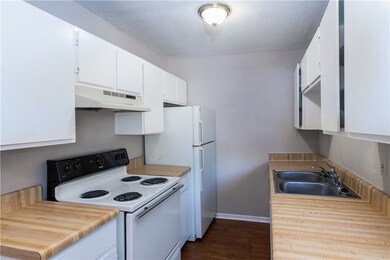 Kitchen featuring a sink, white appliances, basebo