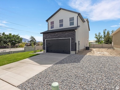 View of side of home featuring an attached garage, concrete driveway, a mountain view, and stone siding