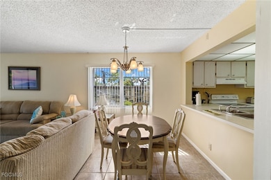 Dining area with light tile patterned floors, a chandelier, and a textured ceiling