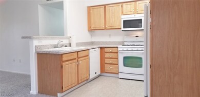 Kitchen featuring white appliances, light brown ca
