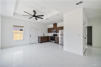 Kitchen with a raised ceiling, light countertops, ceiling fan, stainless steel appliances, and light marble finish floors