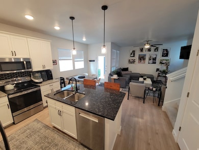 Kitchen featuring appliances with stainless steel finishes, open floor plan, white cabinets, light wood-type flooring, and recessed lighting
