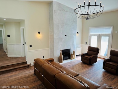 Living area featuring a wainscoted wall, dark wood-style flooring, a tiled fireplace, a decorative wall, and radiator