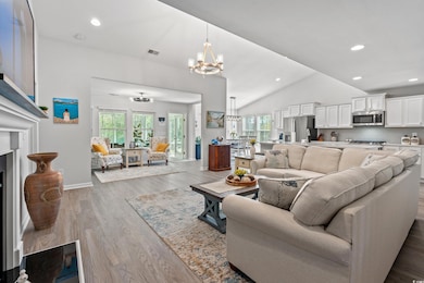 Living room featuring a chandelier, healthy amount of natural light, vaulted ceiling, wood finished floors, and recessed lighting