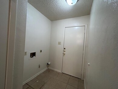 Washroom featuring a textured ceiling, light tile patterned flooring, a textured wall, hookup for an electric dryer, and washer hookup