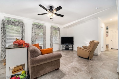 Living room featuring crown molding, plenty of natural light, and ceiling fan