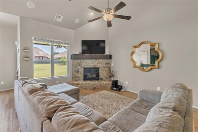 Living room with a fireplace, wood-type flooring, ceiling fan, and vaulted ceiling