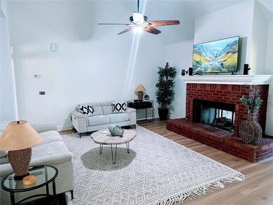 Living room with ceiling fan, vaulted ceiling, a fireplace, and hardwood / wood-style flooring