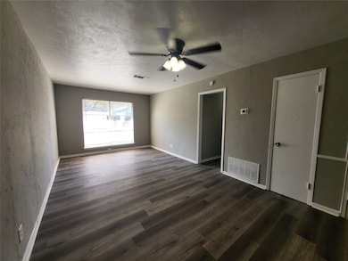 Spare room with a textured ceiling, ceiling fan, dark wood finished floors, and a textured wall
