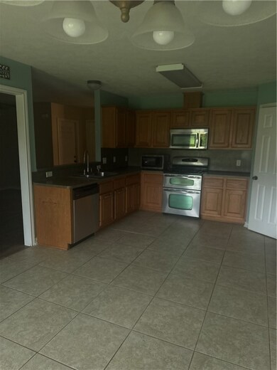 Kitchen featuring stove, dishwasher, light tile pa