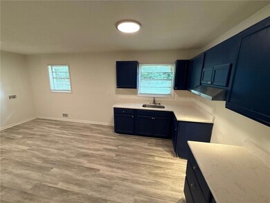 Kitchen featuring blue cabinetry, light wood-style floors, plenty of natural light, and under cabinet range hood