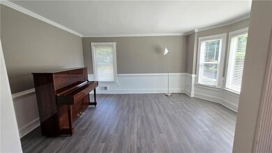 Unfurnished room featuring dark wood finished floors, healthy amount of natural light, crown molding, and baseboards